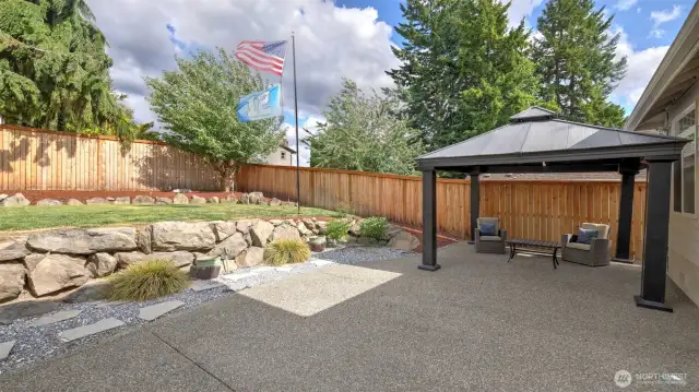 Step out onto the concrete backyard area featuring a spacious, dark-toned gazebo that remains with the home. Plenty of room to relax, enjoy the outdoors, and host gatherings or BBQs