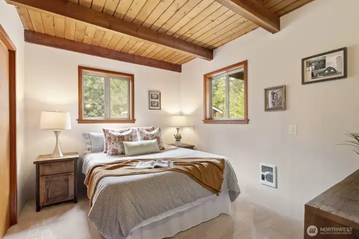Spacious main-floor bedroom with wood-planked ceilings, exposed beams, and a generous closet.