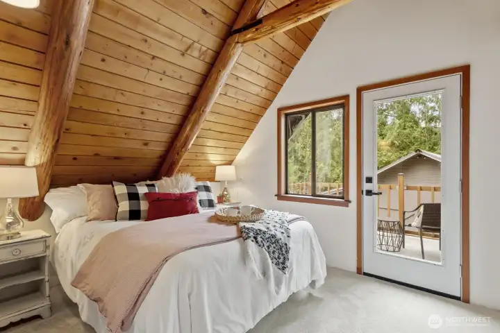 Spacious upstairs bedroom with vaulted wood-planked ceilings and direct access to the upper deck.