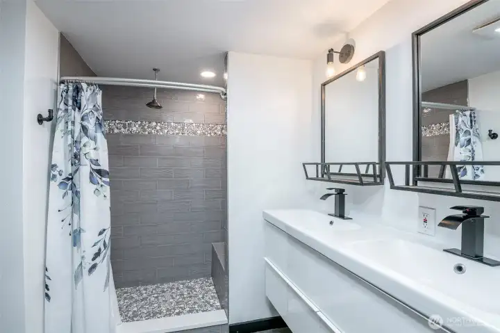 Fully tiled shower in primary bathroom with rain shower head