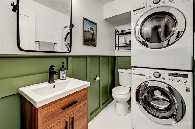 Convenient half bath with full-size washer and dryer. The wooden wainscot and penny tile ceramic floors add to the charm.