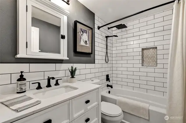 Stunning updated full bathroom with a deep soaking tub with subway tile surround, a stone countertop vanity, and hex tile floors.