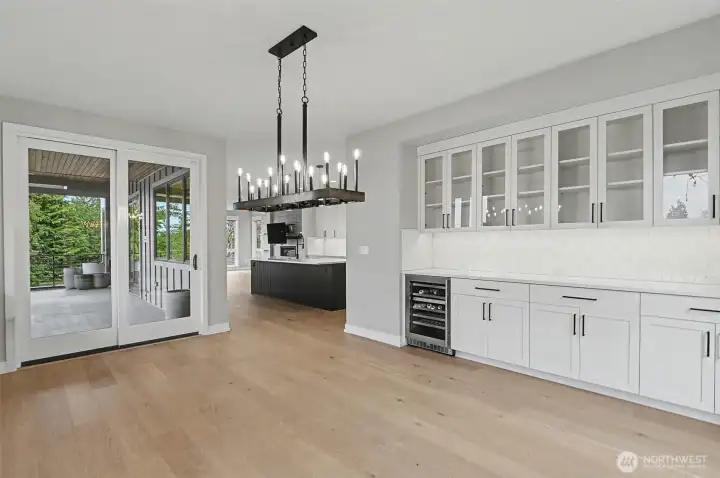 The dining room pairs elegance and function with built-in dinnerware storage, a dramatic chandelier, patio access, and a wine fridge ready for hosting.
