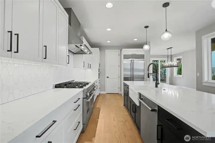 The chef’s kitchen pairs stainless steel appliances with sleek countertops, striking dual-toned cabinetry, and generous pantry storage.