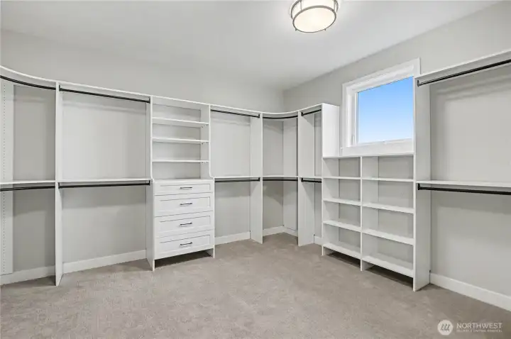 Massive walk-in primary closet with a window that fills the space with natural light, combining style and functionality.