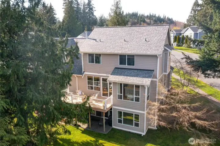 Rear view of home showing deck, patio, daylight basement and fully fenced yard