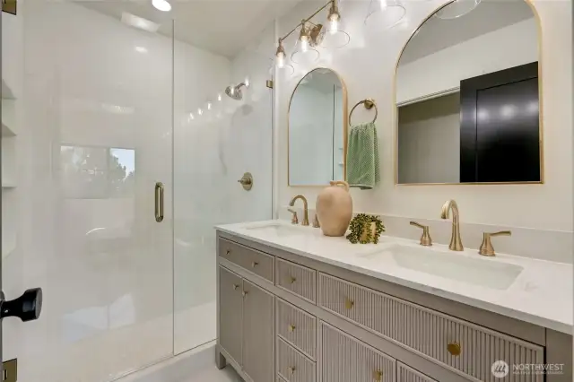 Primary bathroom - STUNNING custom  shower with double vanity & custom gold  features. Incredible attention to detail in this  ensuite, including built-in shelving in the  primary shower.