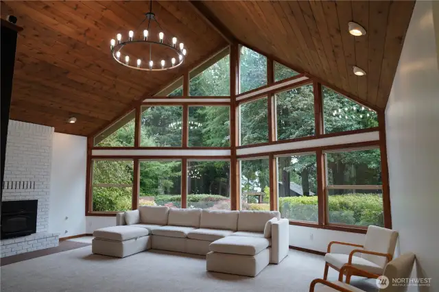 The living room is a stunner and offers a cozy ambiance, featuring a large cathedral ceiling, chandelier, and wood-burning fireplace insert. Enjoy a beautiful view to the garden outside.