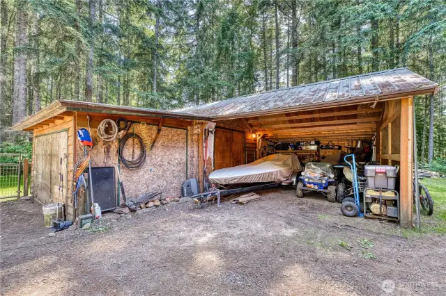 Detached carport for 2 cars with attached shop space.