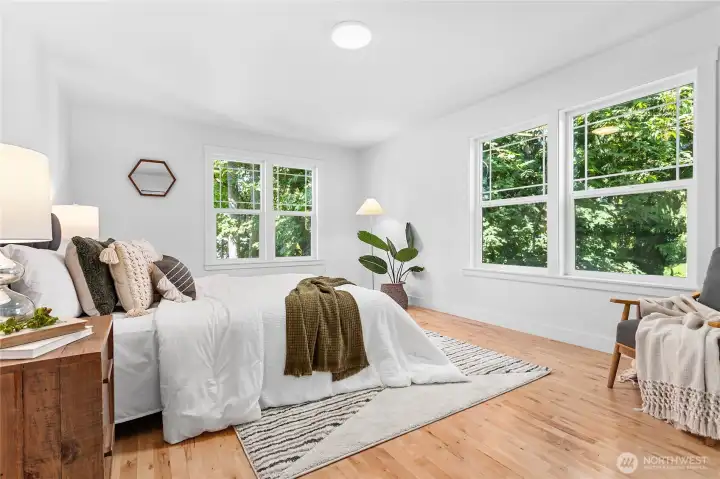 Gigantic main level primary bedroom with large picture windows overlooking the greenspace and creek below it.