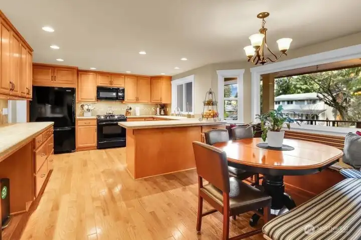 Spacious Kitchen with wood cabinetry, center peninsula, built-in bench seating and large bay windows with a view of the cascades.