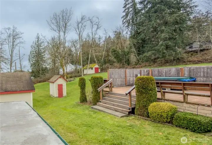 Side yard view of hot tub deck, garage, and storage shed.