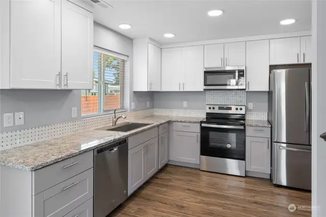 Shaker cabinets in two colors providing storage above and below granite countertops.  Stainless steel appliances.