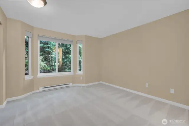 Primary bedroom overlooks a lush backdrop.