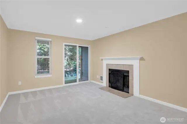 The living room is warmed by a cozy fireplace. A slider opens to the patio.