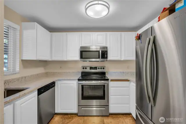 Inviting kitchen with white cabinetry, stainless appliances, and granite countertops.