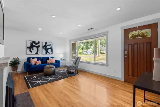 Bright and welcoming front room with beautiful hardwood floors and oversized windows that flood the space with natural light.