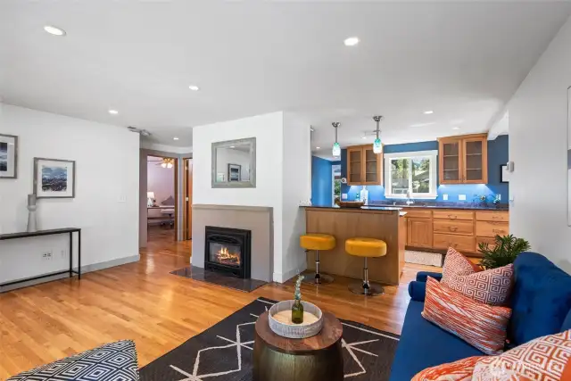 Open sightlines into the kitchen, where a cozy bar offers extra seating and stylish lighting adds a touch of charm.