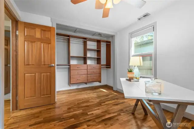 Comfortable and well-appointed bedrooms featuring hardwood floors, a ceiling fan, solid wood doors, and a built-in closet organizer to keep everything tidy.