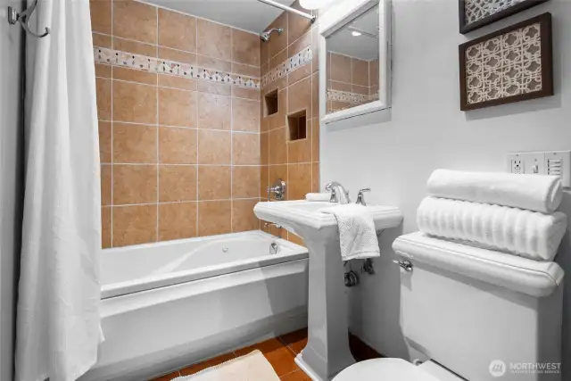 Beautifully updated guest bath featuring custom tilework, a relaxing jetted tub, and heated tile floors for spa-like comfort.