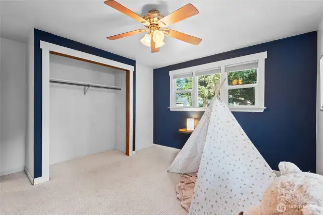 Ceiling fans adds comfort on warm summer nights—keeping this bright bedroom cool and breezy.