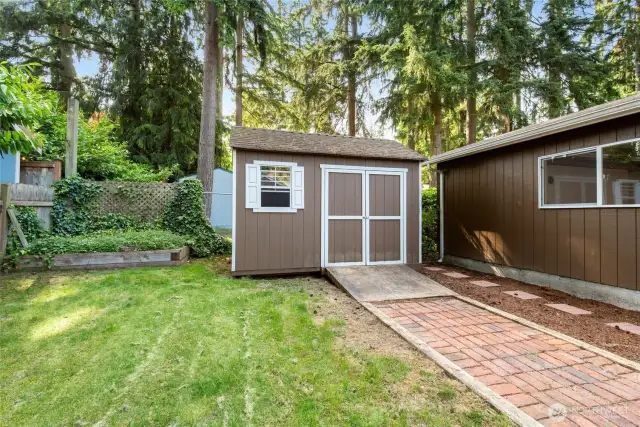 Raised garden bed is ready for your green thumb, with a dry storage shed nearby to keep tools and supplies close at hand.