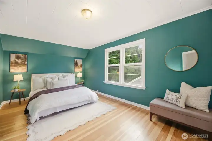 Large, beautiful primary bedroom with original hardwood flooring.