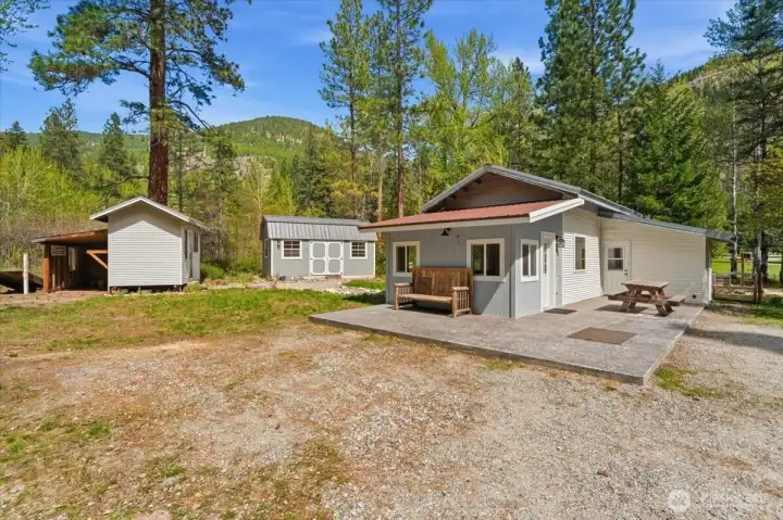Tiny home with stamped concrete patio and two of the three outbuildings.