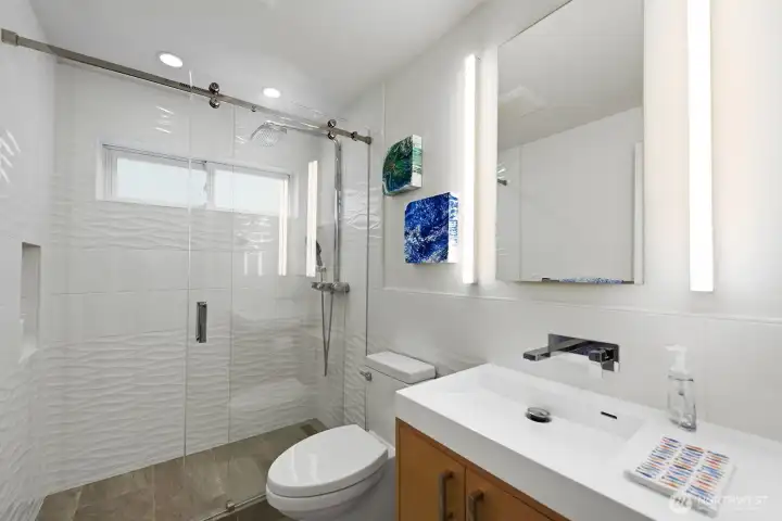 Completely renovated guest bath also serves the living area. Custom cabinets, quartz countertops, Hansgrohe fixtures, tiled throughout.