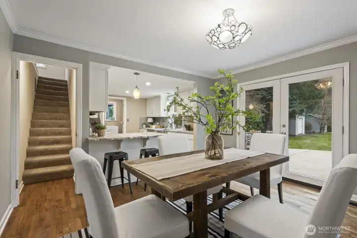 An open living and dining area flow seamlessly together, with French doors opening to the outdoor stamped concrete patio.