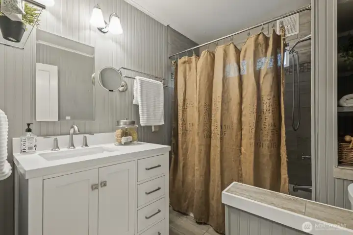 Spa-inspired updated bath featuring a cast iron tub, custom tile & quaint linen storage on main floor.