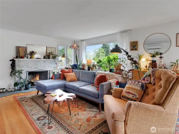 Bright living room featuring large picture windows with views of the spacious backyard and a cozy wood-burning fireplace ideal for chilly evenings.