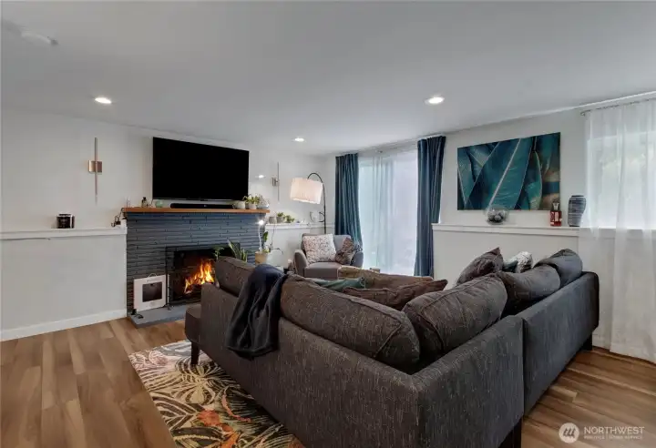 Living room featuring a wood-burning fireplace and sliding door to a fenced-in patio area, conveniently located off the kitchen for easy entertaining