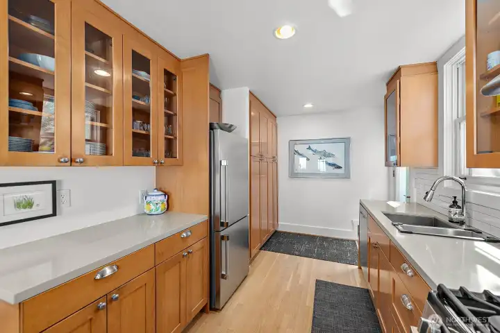 Here you can see the built-in pantry cabinets at the rear of this photo and this photo also shows the quartz countertops for a touch of elegance. The refrigerator is newer and has large capacity in both the frig & the freezer spaces.