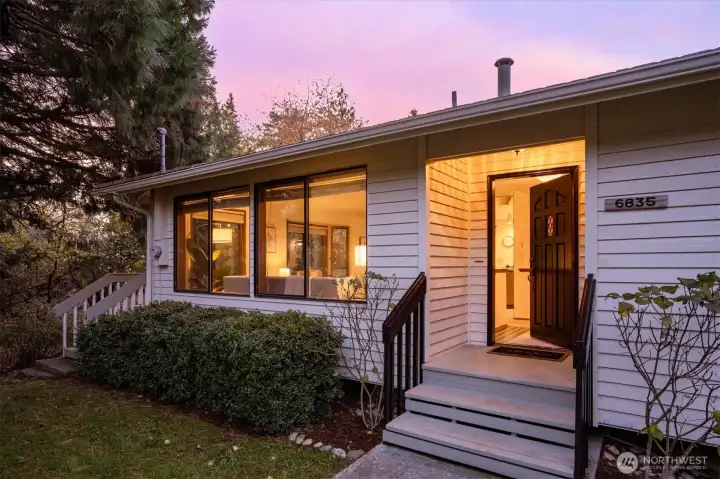 After the tunnel of trees guides you home the entry glows at dusk with warm light and tidy landscaping echoing the same calm welcome found throughout the residence.