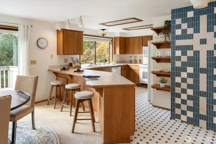 A spacious kitchen designed for everyday ease with a breakfast bar and open storage all set against leafy views of the pastoral half acre.