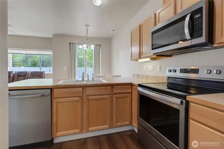 Kitchen featuring stainless steel appliances, warm maple cabinetry, and a tile backsplash, combining functionality with a clean, classic look.