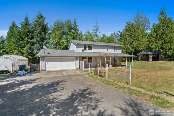 House with fenced yard. Greenhouse on left and 20x28 covered area on right.