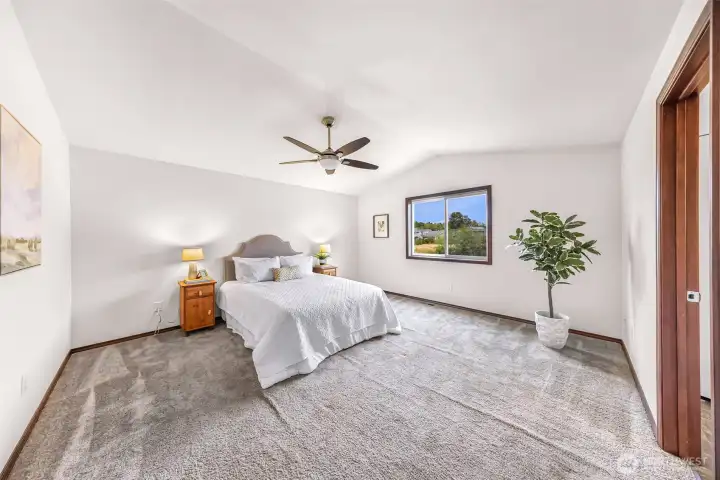 Primary bedroom with a large east facing window, a light/fan fixture and it's ensuite bathroom to your right.