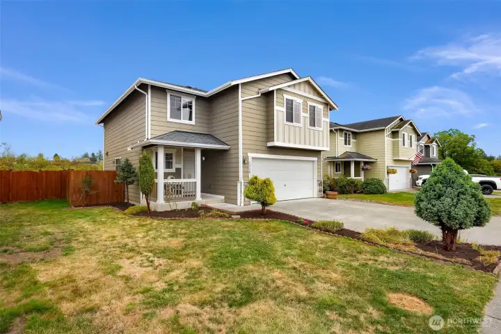 Side yard of home seen here with a fully fenced yard and covered front porch.