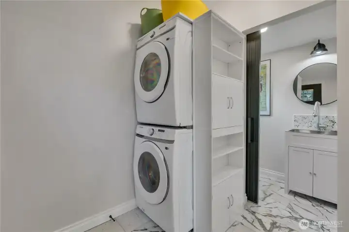 Way back to the kitchen and by the back door, you will find this laundry room and half bath with built-in shelving over and beside the stacking full-size units.