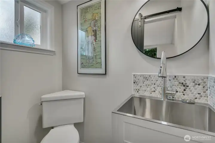 Powder room with a sliding barn door and a deep stainless sink that doubles as a classy utility sink for your day to day needs.  Heated floors extend throughout.