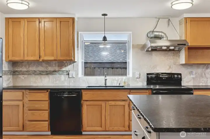 Kitchen with granite counter tops and stone tile backsplash.