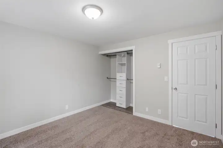 Another view of the primary bedroom, this showing the closet system installed to help manage space.
