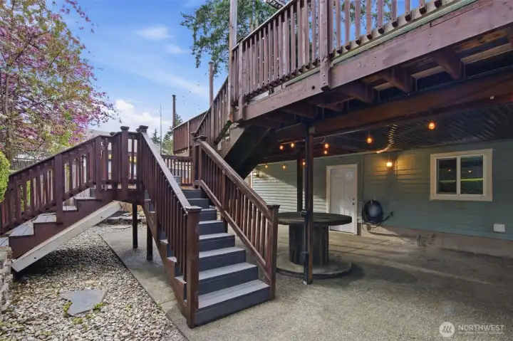 View o the lower level covered patio area and stairs leading up to the main floor massive deck.