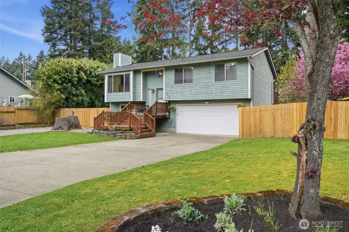 Vie of the beautiful front yard, driveway and entrance to behind the fence or RV storage and extra vehicle storage. Be sure to notice the fresh landscaping and mature trees.