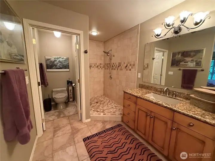 Primary suite with luxurious bathroom with two separate vanities, open shower, gorgeous tile work and private commode.