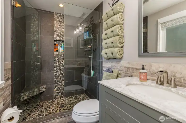 Primary bathroom features a step-in shower with frameless glass door and custom stone details Primary bathroom features a step-in shower with frameless glass door and custom stone details