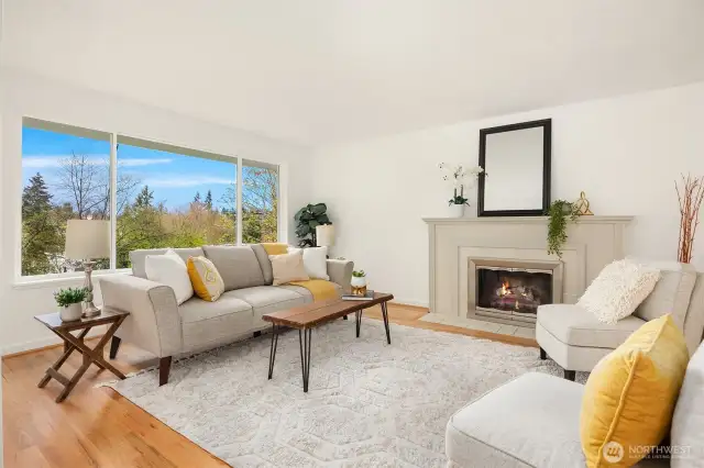 Main level living room with expansive windows overlooking backyard and gas fireplace