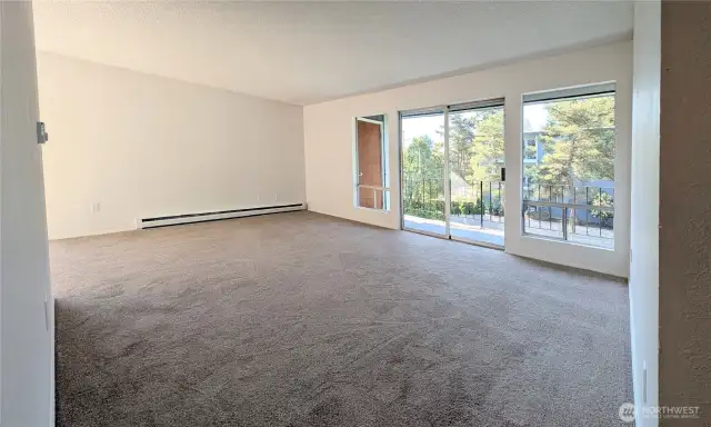 Living area with large windows and sliding door to allow a lot of light. Sliding door opens to balcony. Freshly painted